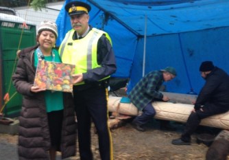 Behind the police tape on Burnaby Mountain a Squamish woman tends a sacred fire in cooperation with the RCMP